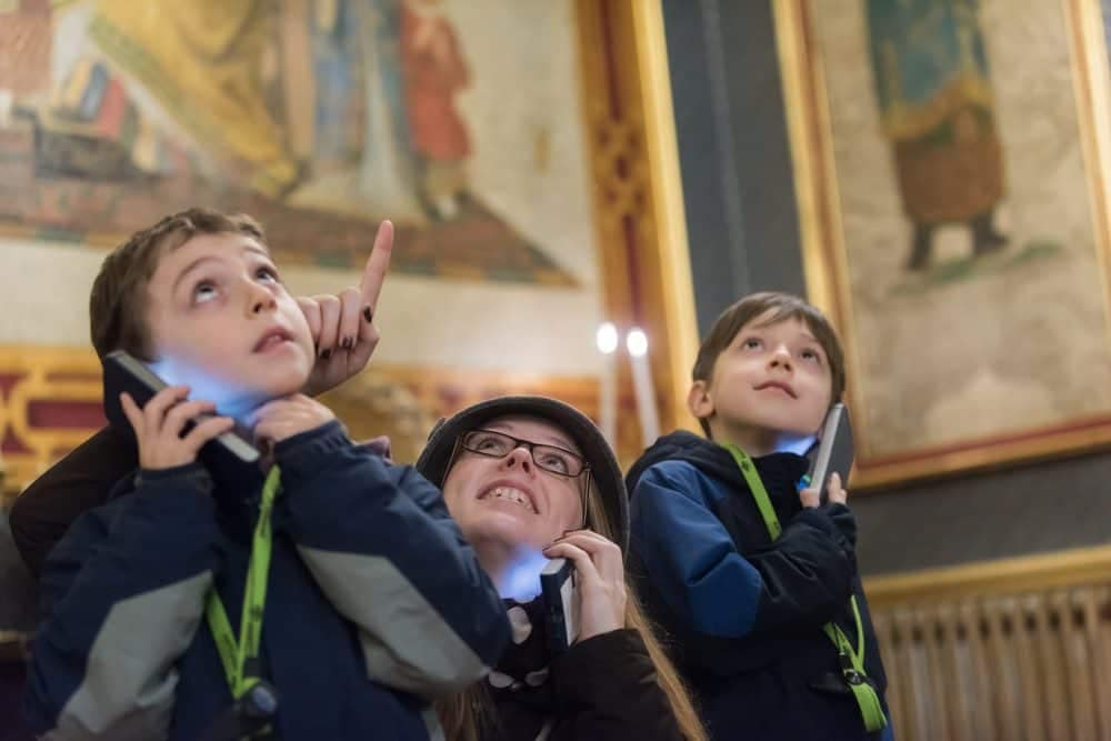 Duas crianças com guia a ouvir um Áudio Guia no museu - Soluções Digitais